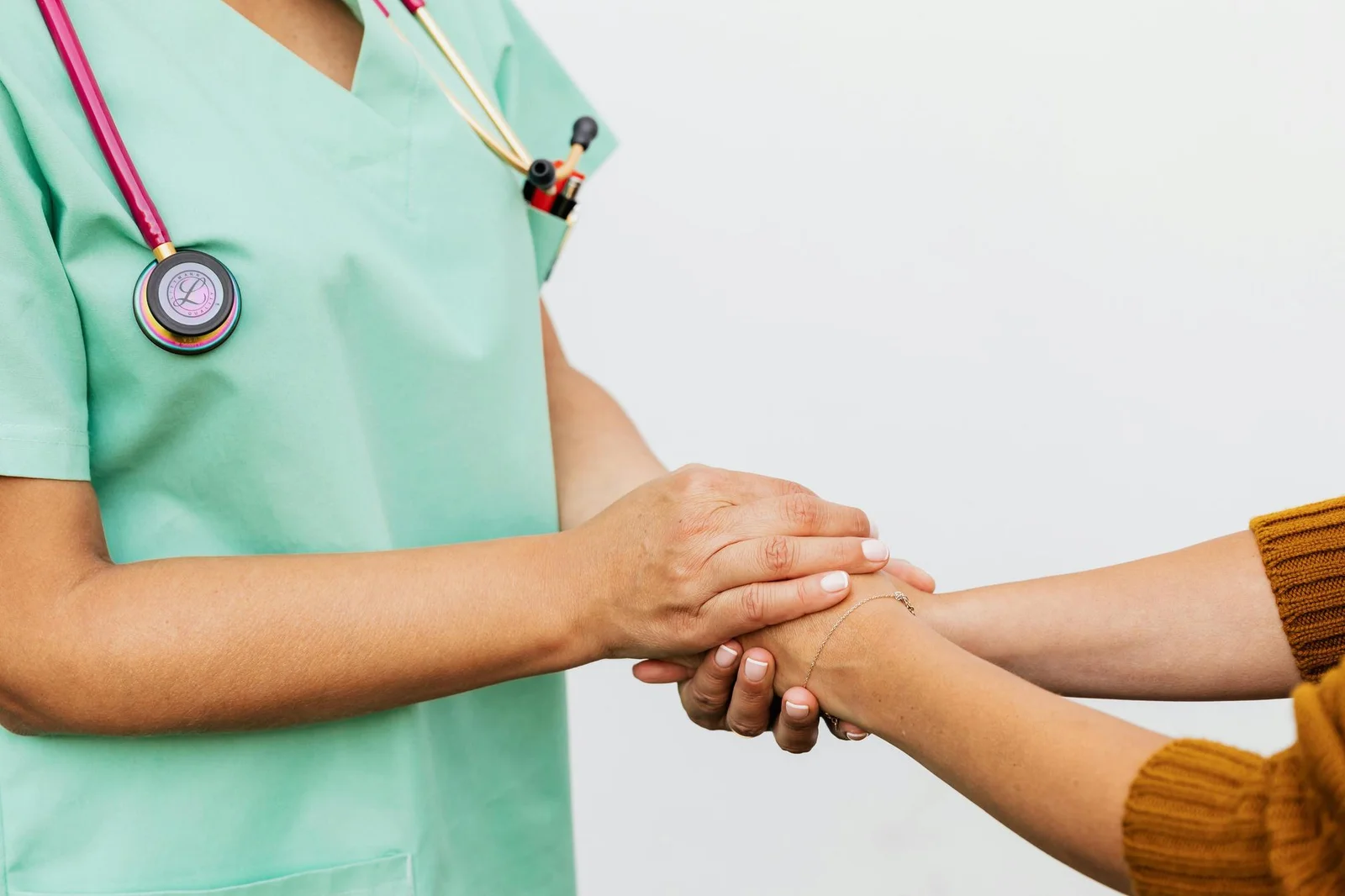 Compassionate Saisha home caregiver holding the hand of an elderly senior patient